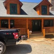 A truck is parked in front of a log cabin.