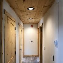 A long hallway with wooden doors and a wooden ceiling.