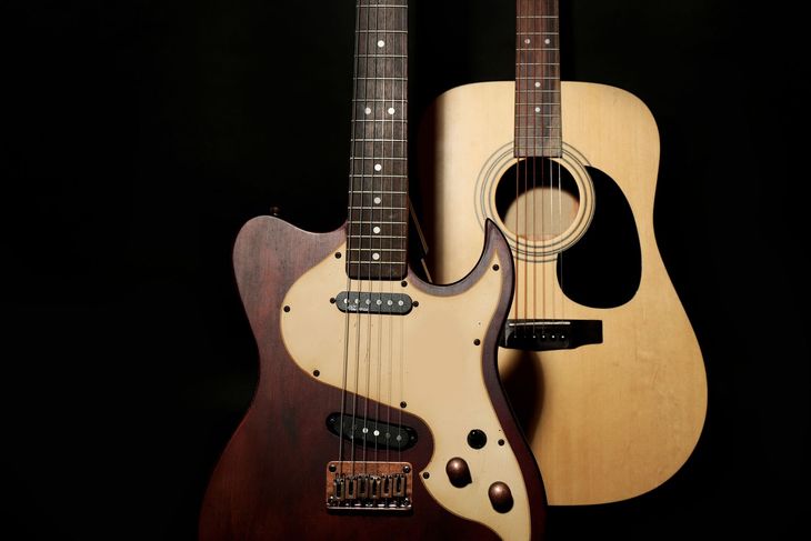 Bass guitar and acoustic guitar against a black backdrop; the electric bass is dark brown and tan.