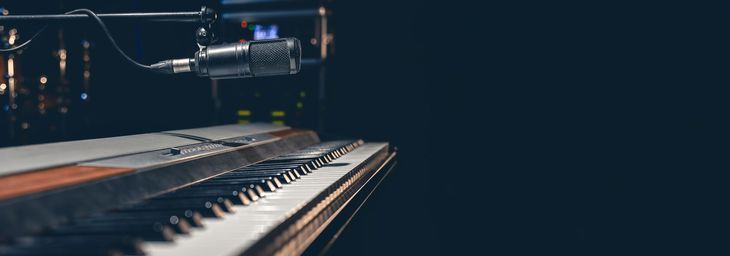 Piano keys with a microphone above them in a dark room.