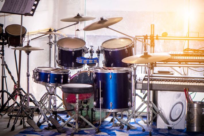 Blue drum kit set up on a stage, with cymbals, sheet music, and stage lights.