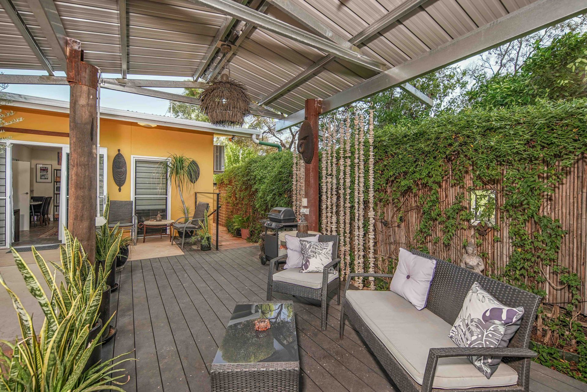 Outdoor patio with gray furniture, wooden deck, and yellow building.