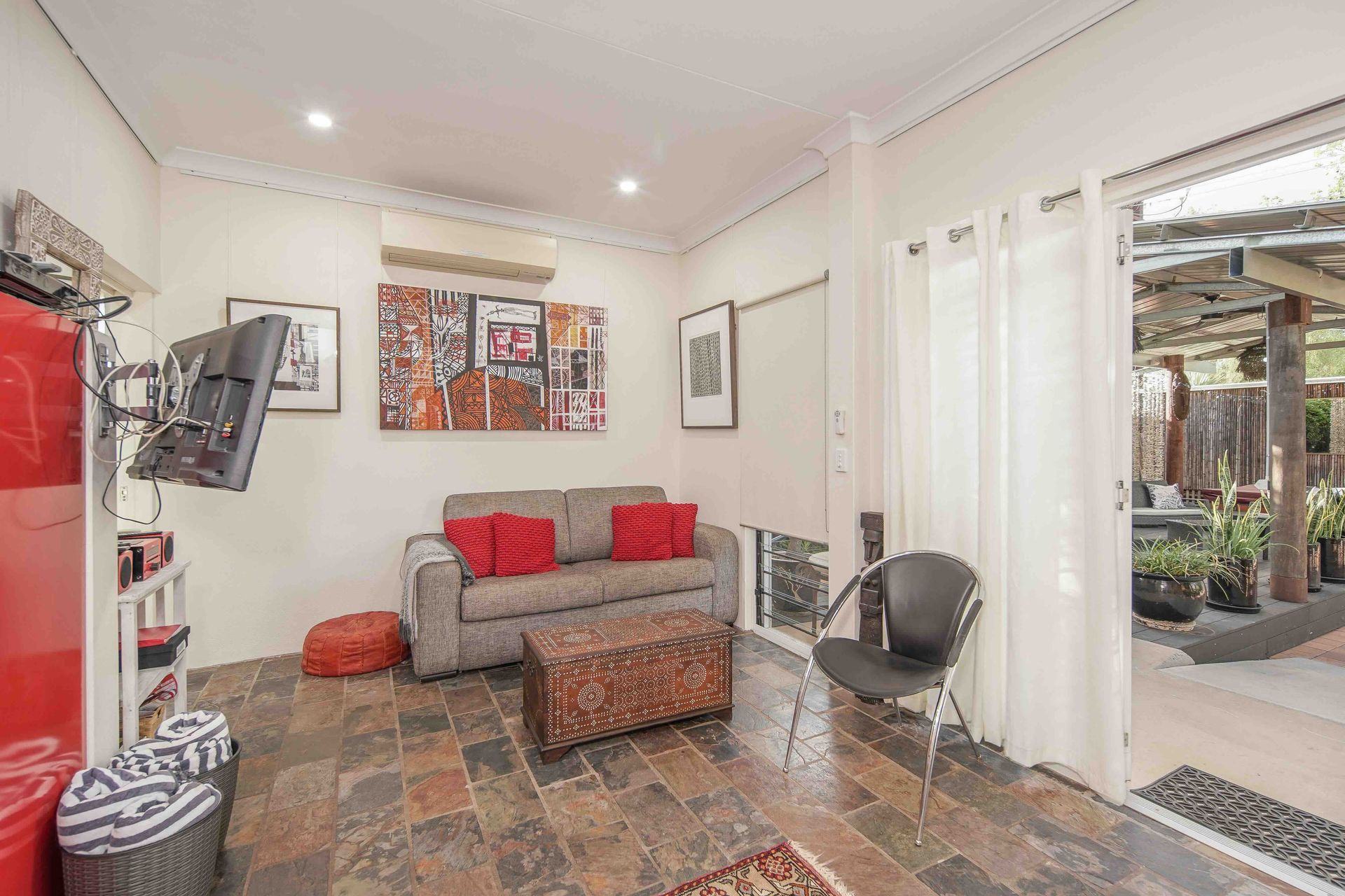 Living room with sofa, red accents, and open door to an outdoor patio area.
