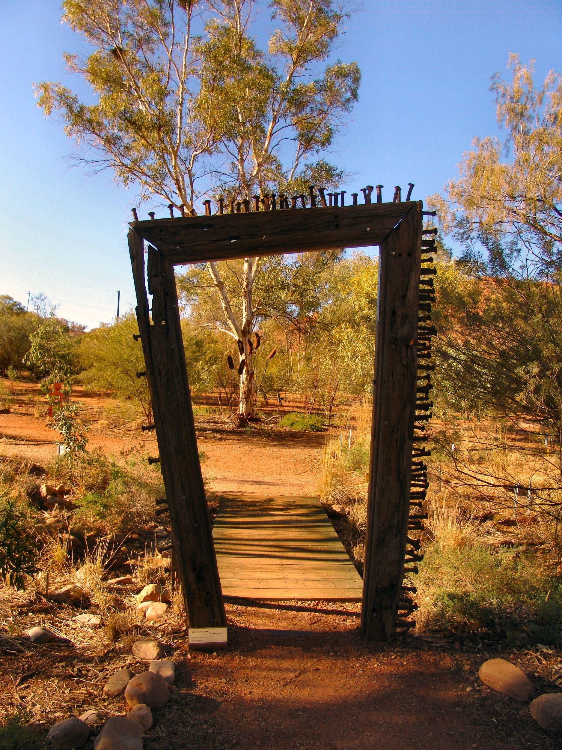 Wooden archway with bridge, in an arid landscape with a blue sky.