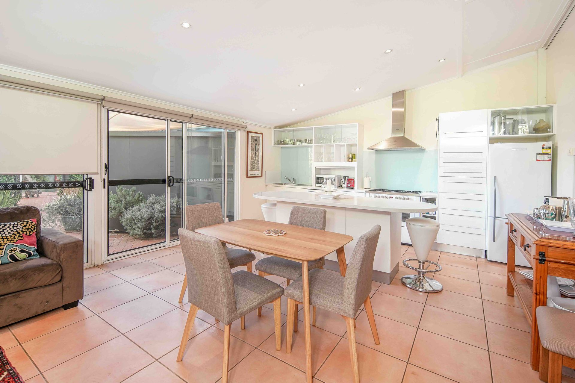 Open-plan kitchen and dining area with sliding doors to a patio. Beige tiled floor.