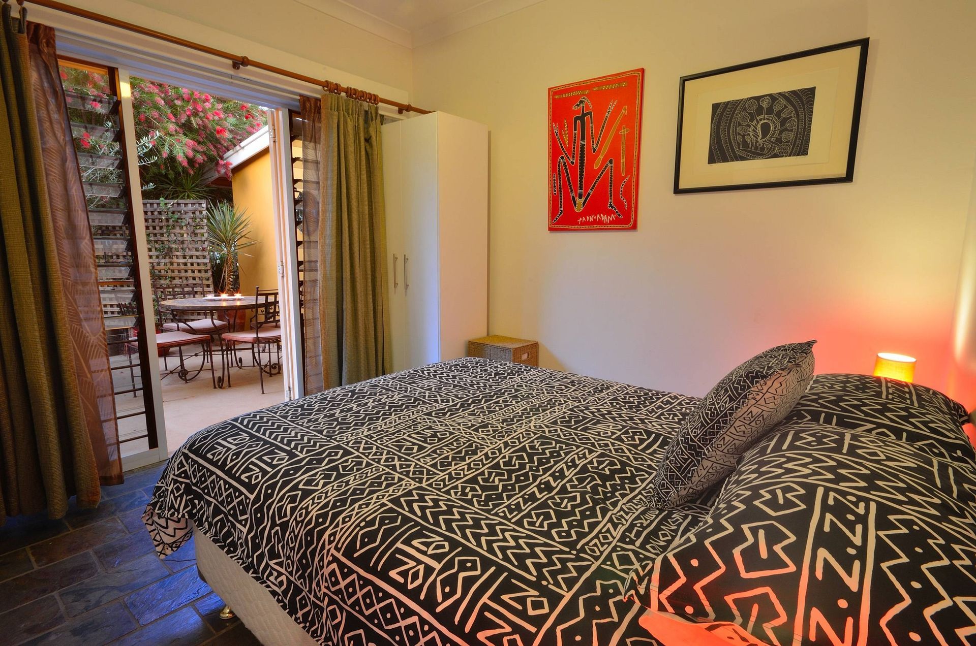 Bedroom with bed, sliding glass door to patio, art on walls.