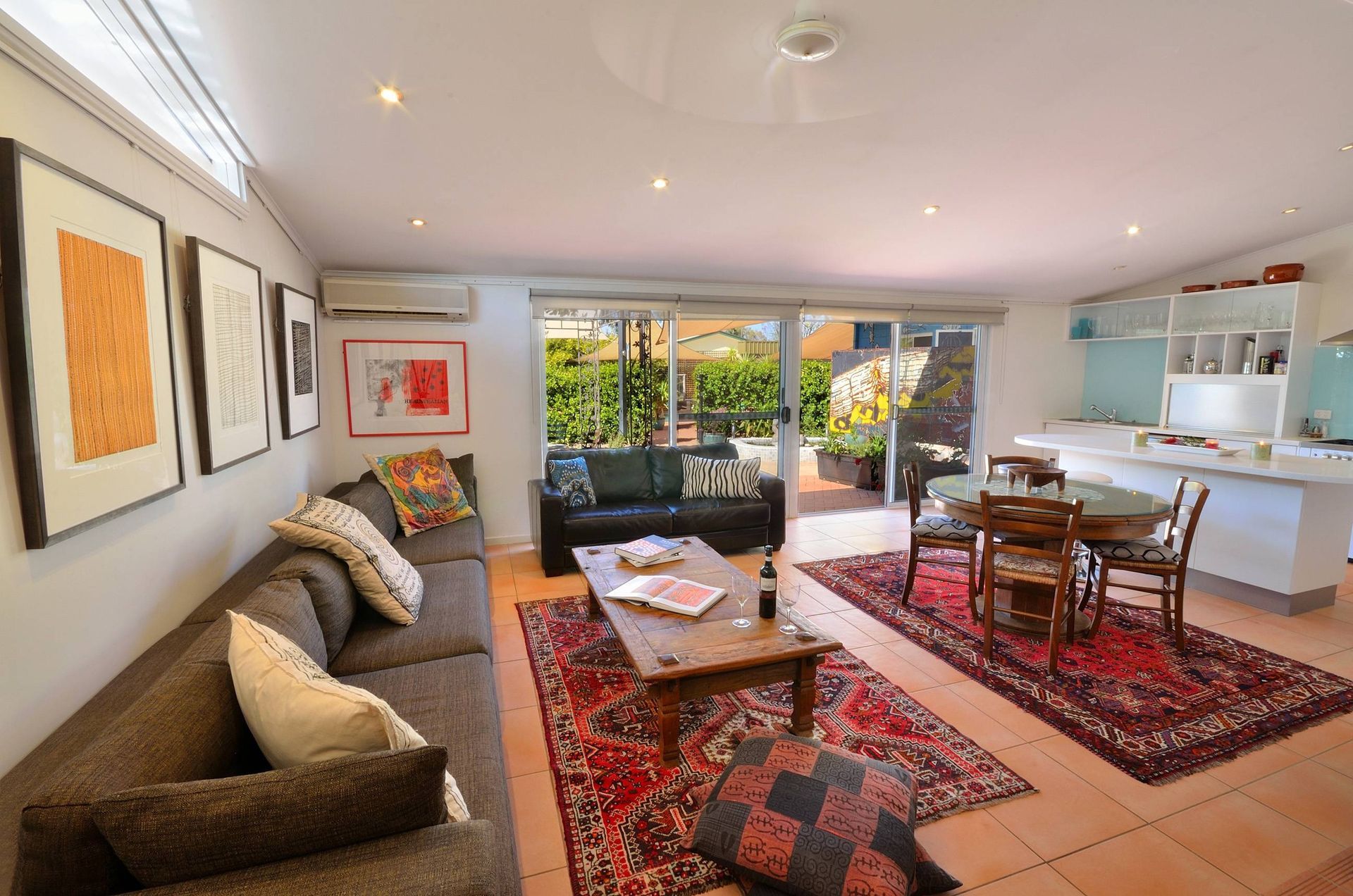 Living room with sectional sofa, rugs, dining table, and sliding glass door to a patio.
