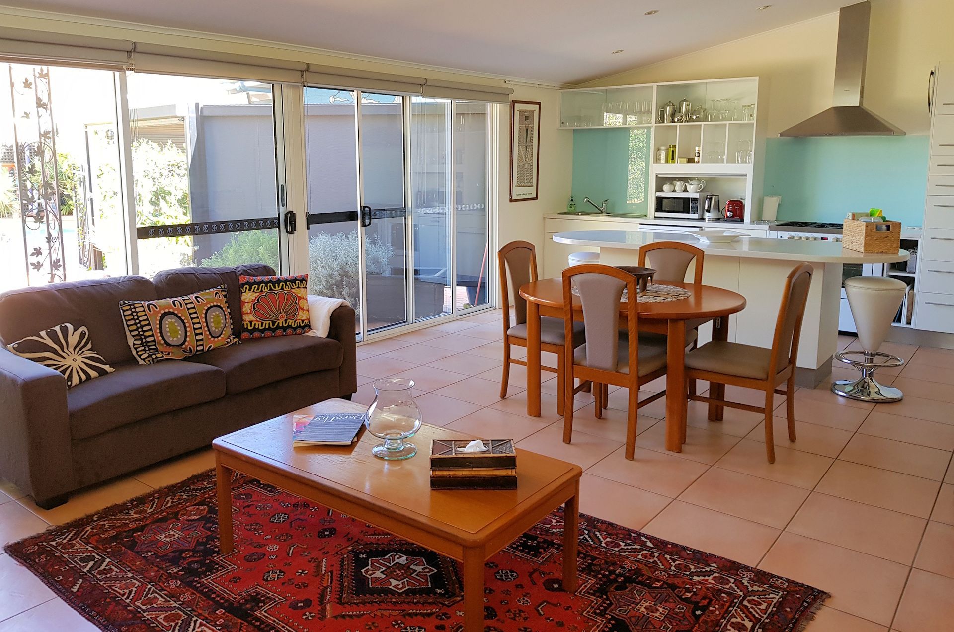 Living room with couch, dining table, kitchen, and large sliding doors.