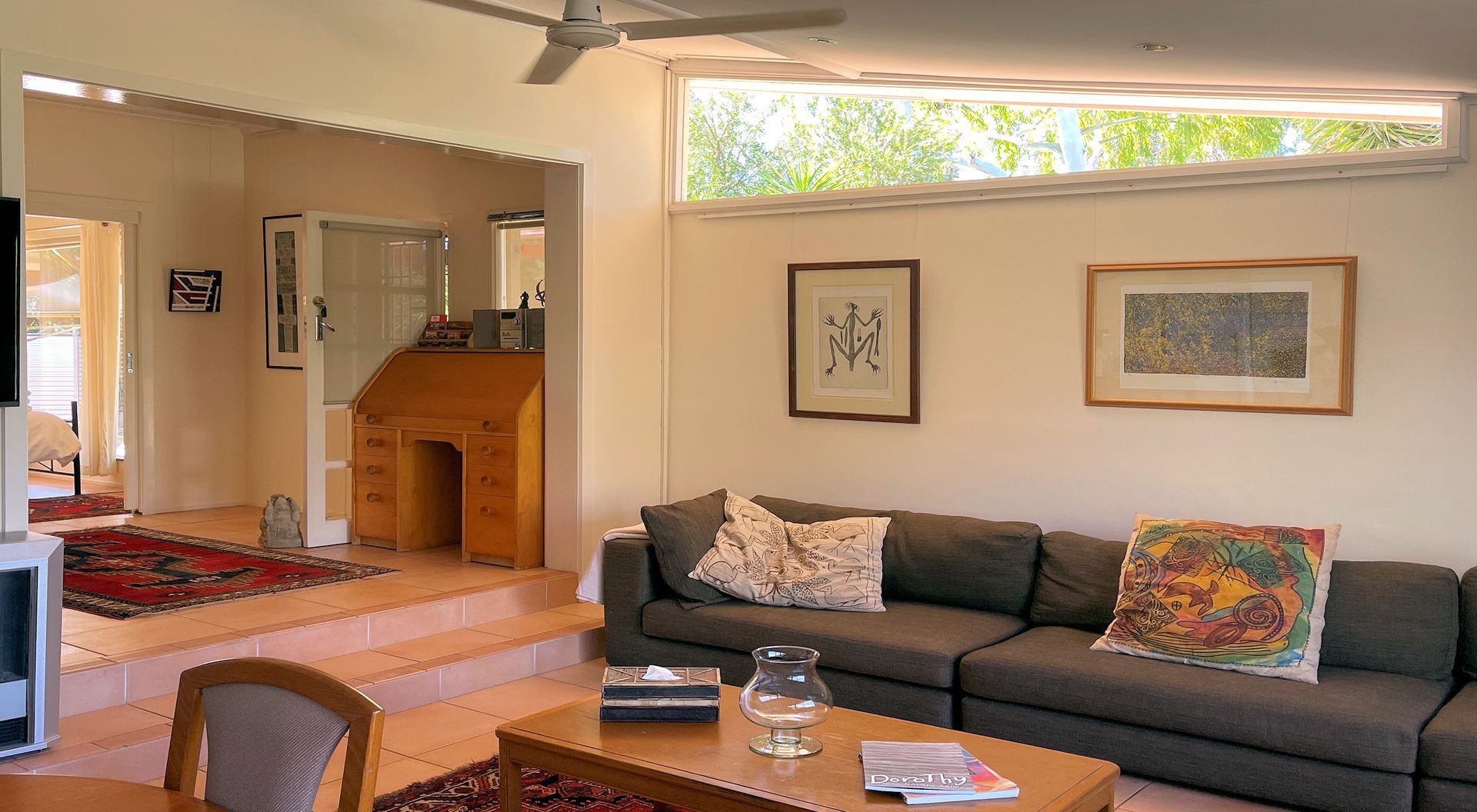 Living room with sectional sofa, desk, art, and clerestory window.