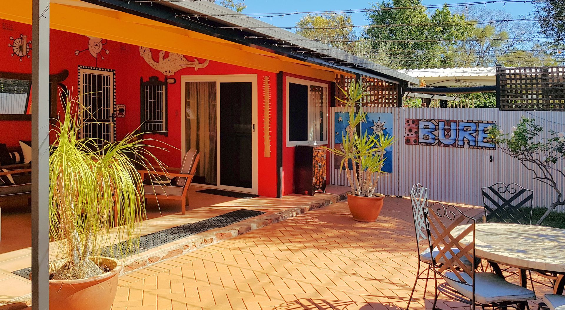 Bright red building with patio, outdoor seating, and a white fence with 