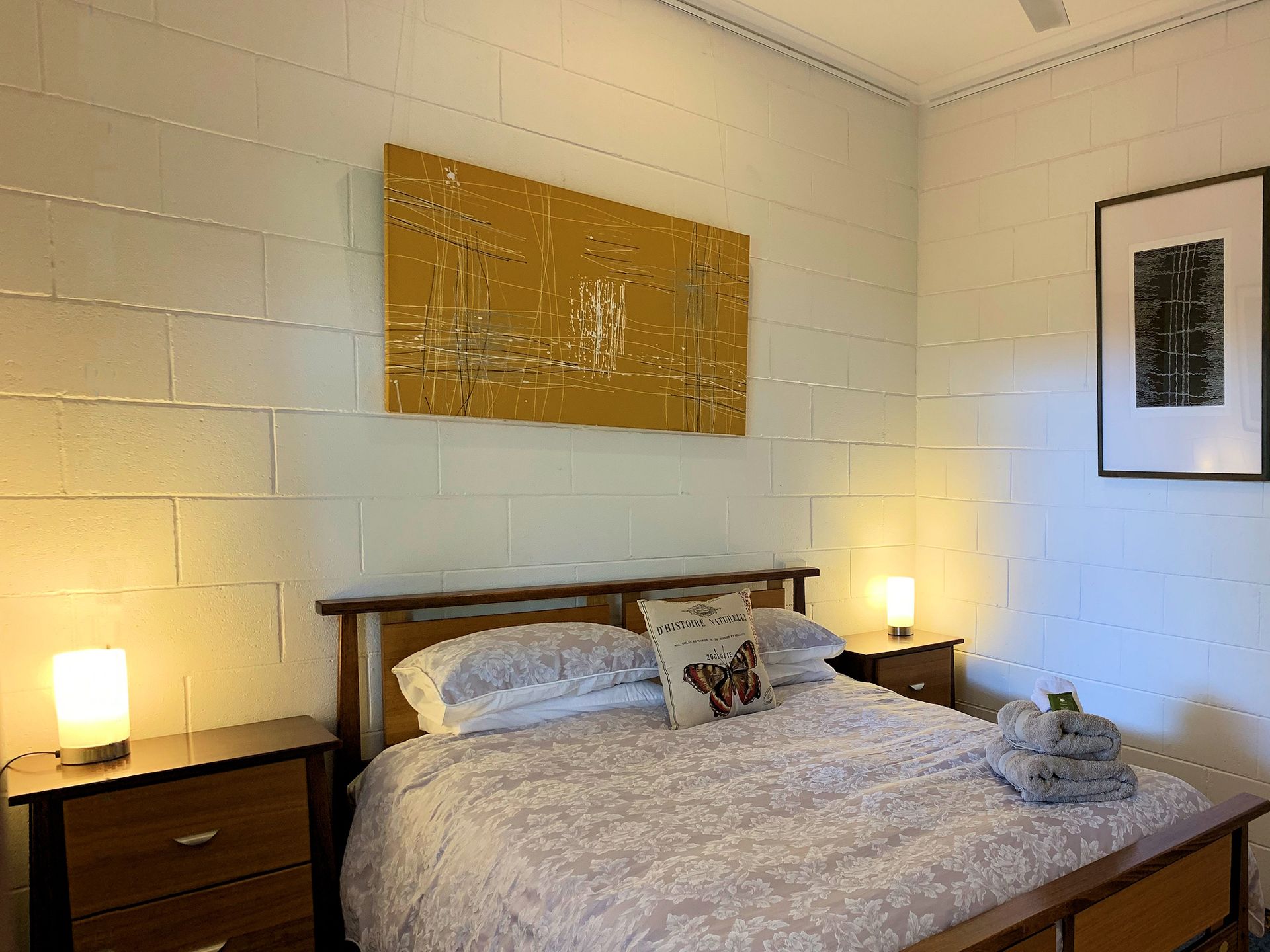 Bedroom with a double bed, two bedside tables with lamps, and artwork on the wall.