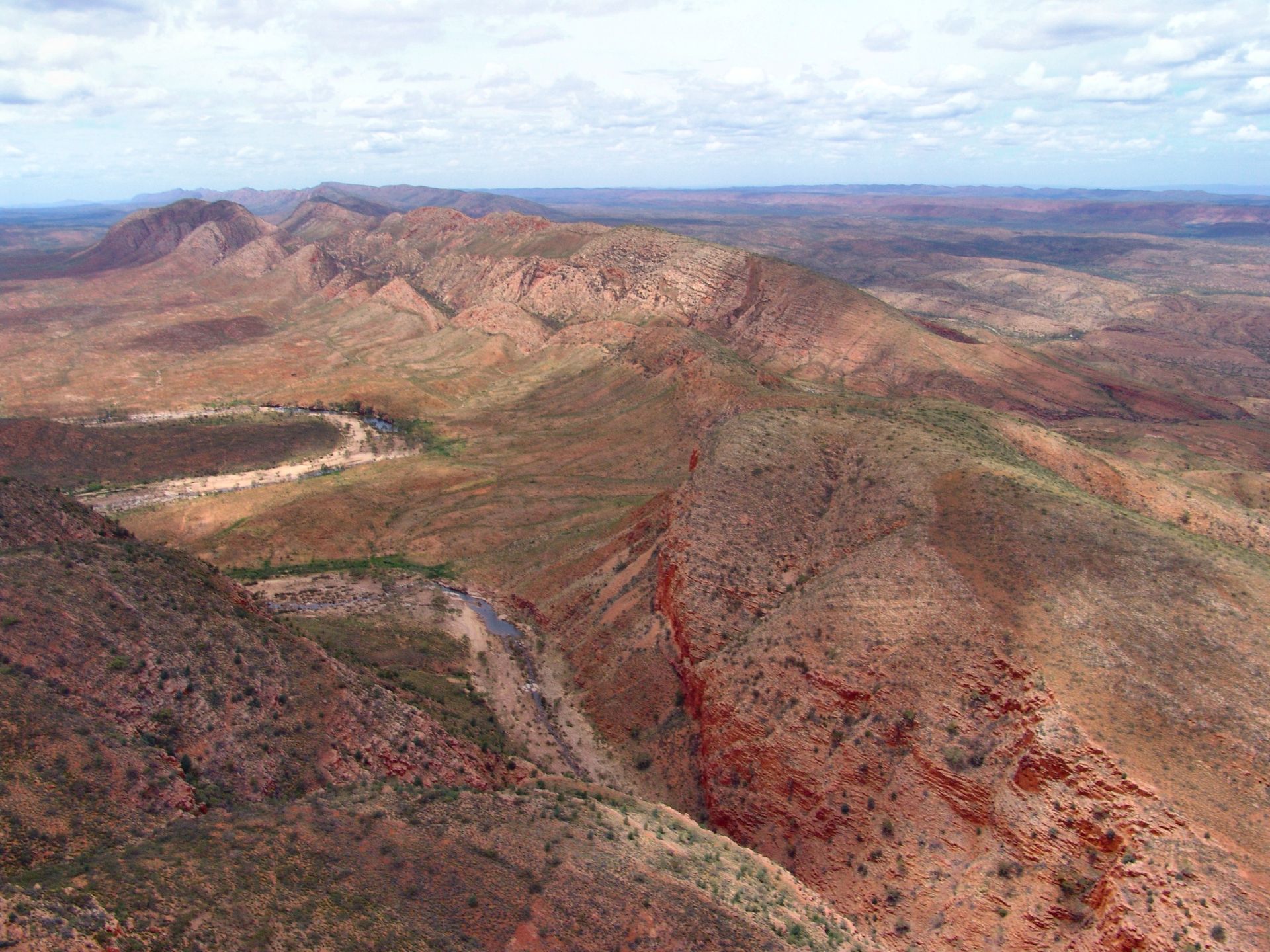 Red rock mountains and arid landscape under a cloudy sky.