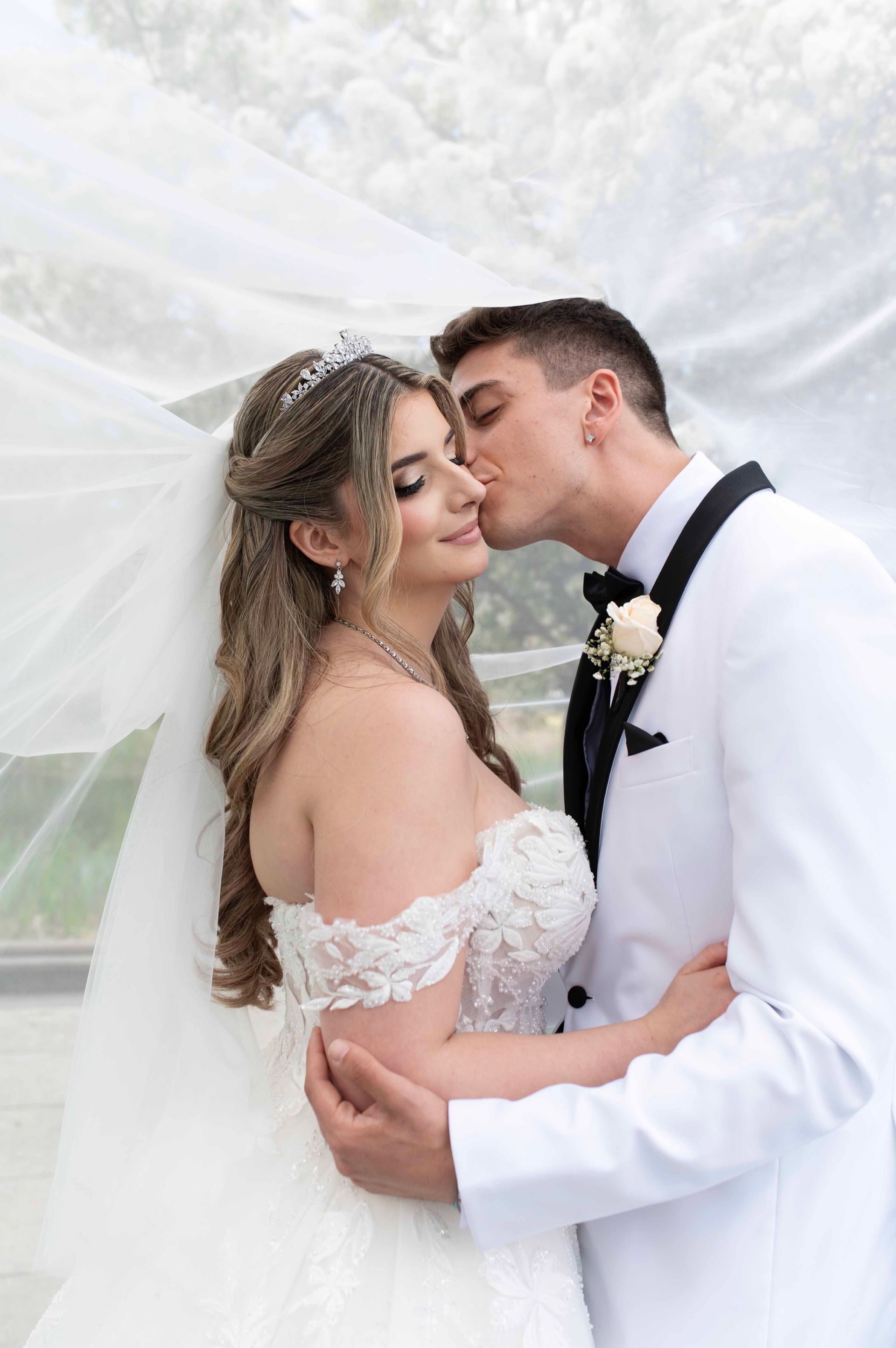 Bride and groom sharing a kiss under a white draped canopy