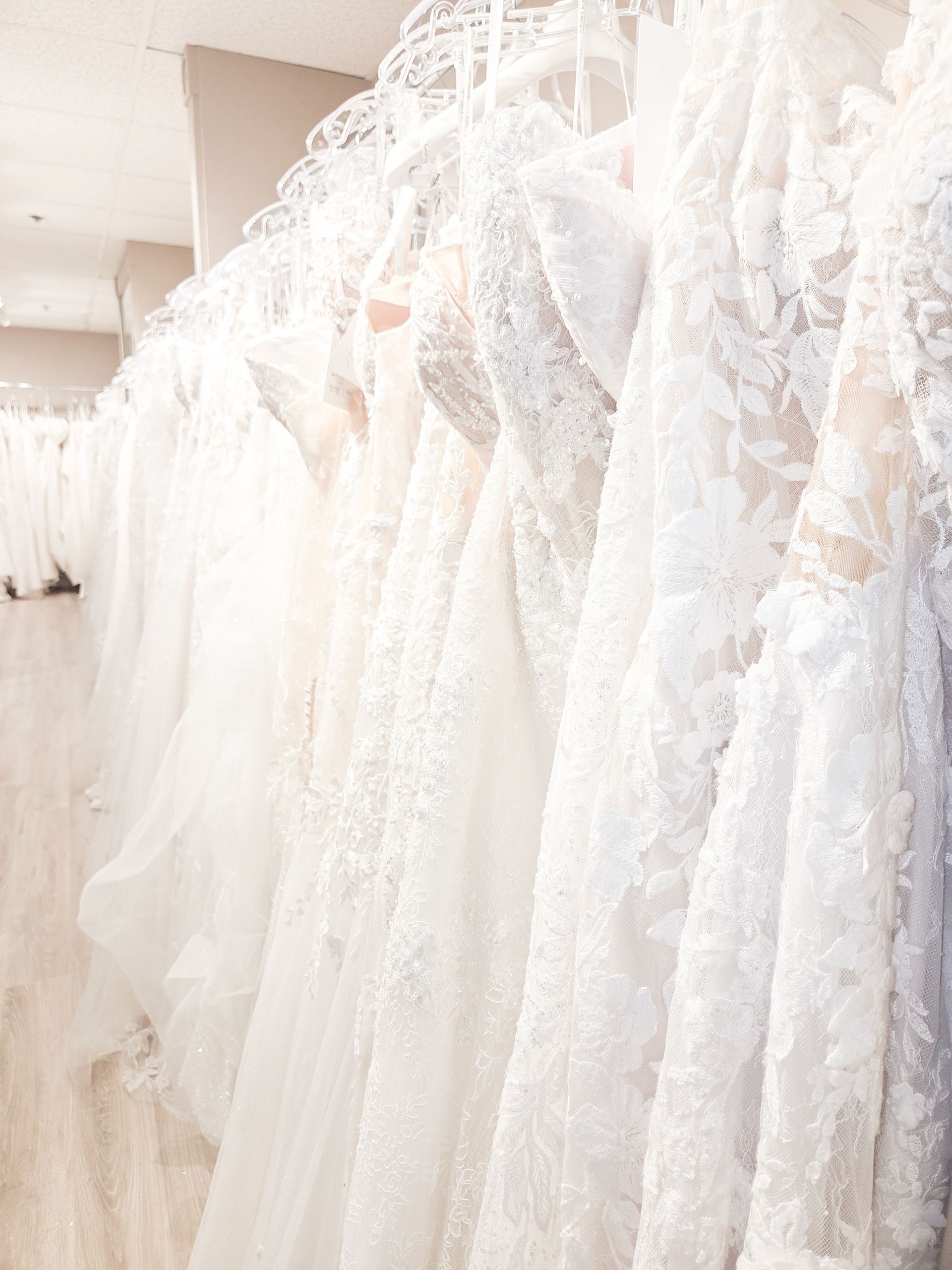 A row of white lace wedding dresses hanging in a bridal boutique