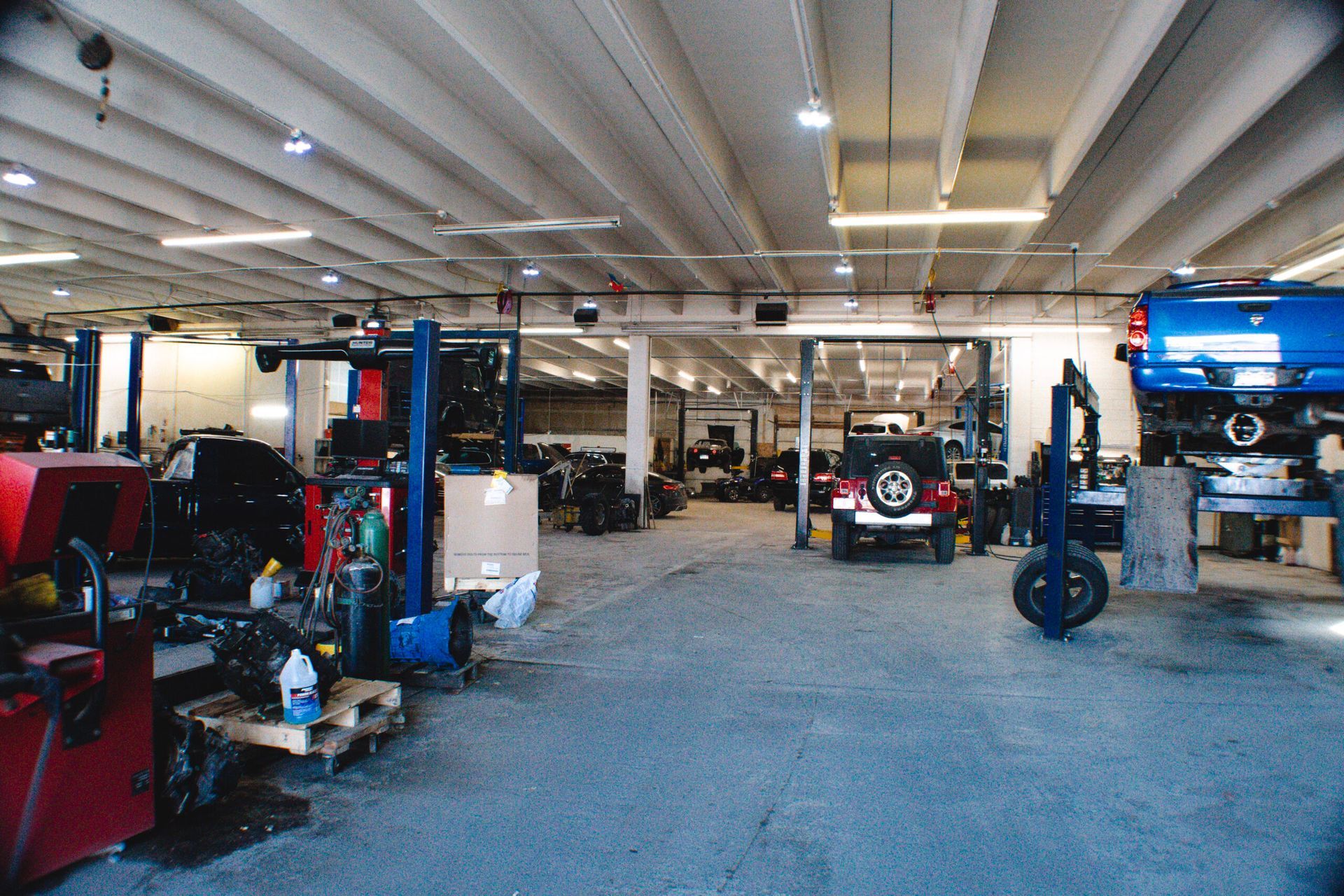 Automotive repair shop with vehicles on lifts, tools, and a blue floor inside a large garage | Accurate Automotive Northglenn
