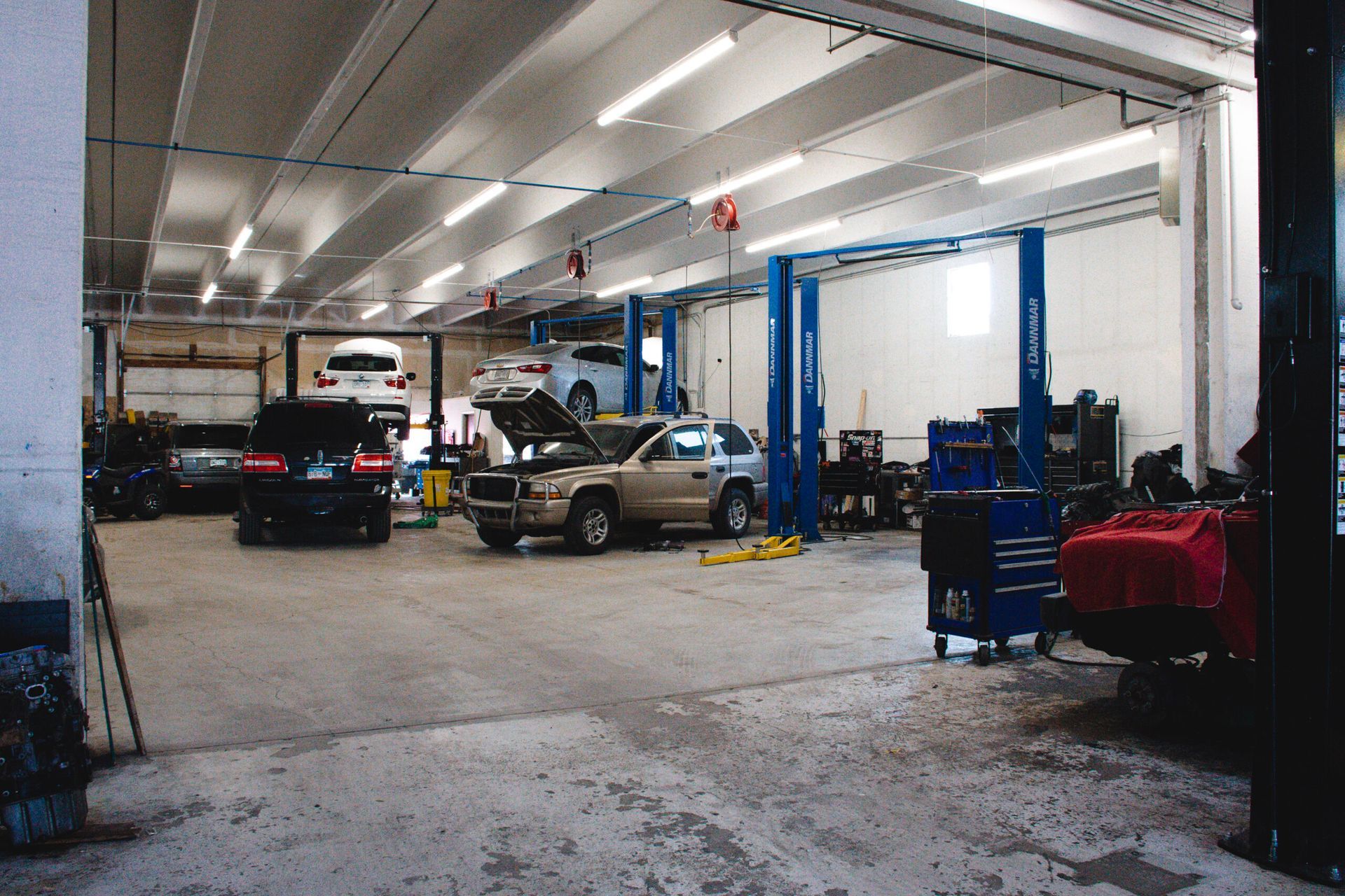 Auto repair garage with cars on lifts, blue tool carts, and bright overhead lights | Accurate Automotive Northglenn