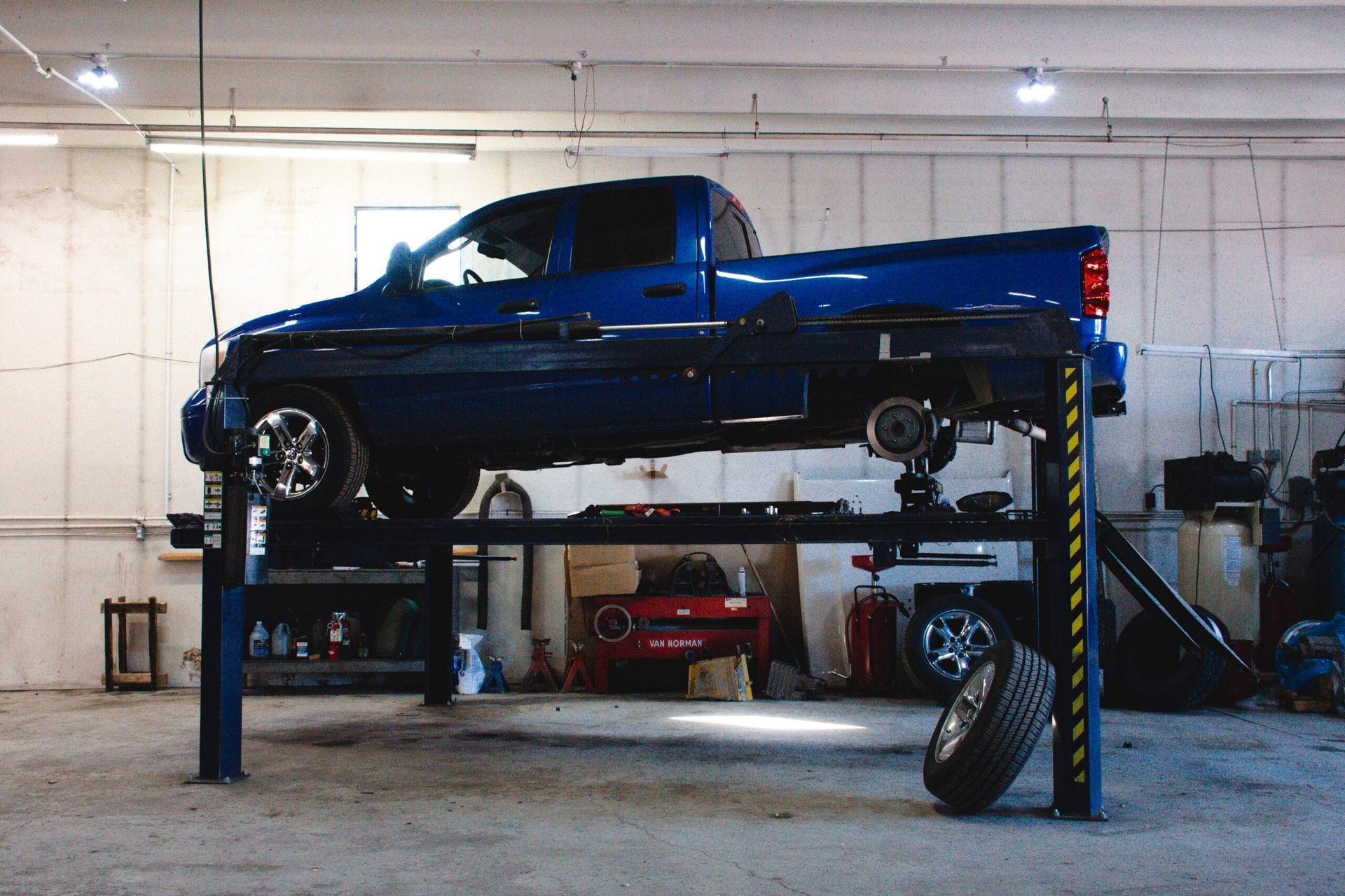 Blue pickup truck lifted on a vehicle hoist in an auto repair garage | Accurate Automotive Northglenn