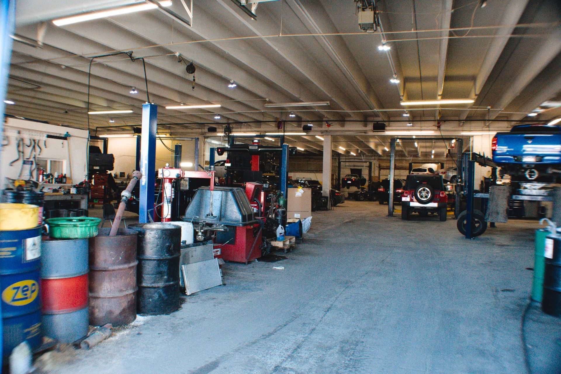 Auto repair garage with cars, tools, and stacked barrels inside a spacious workshop | Accurate Automotive Northglenn