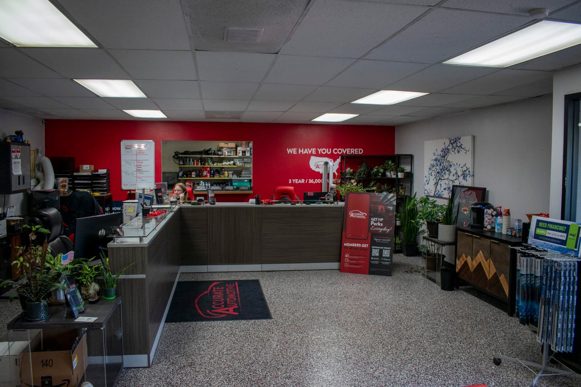 Small shop counter with shelves, red back wall, and display items in a bright interior | Accurate Automotive Northglenn