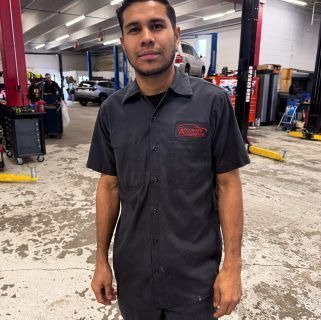 Mechanic standing in an auto repair shop, wearing a dark work shirt and pants. | Accurate Automotive Northglenn