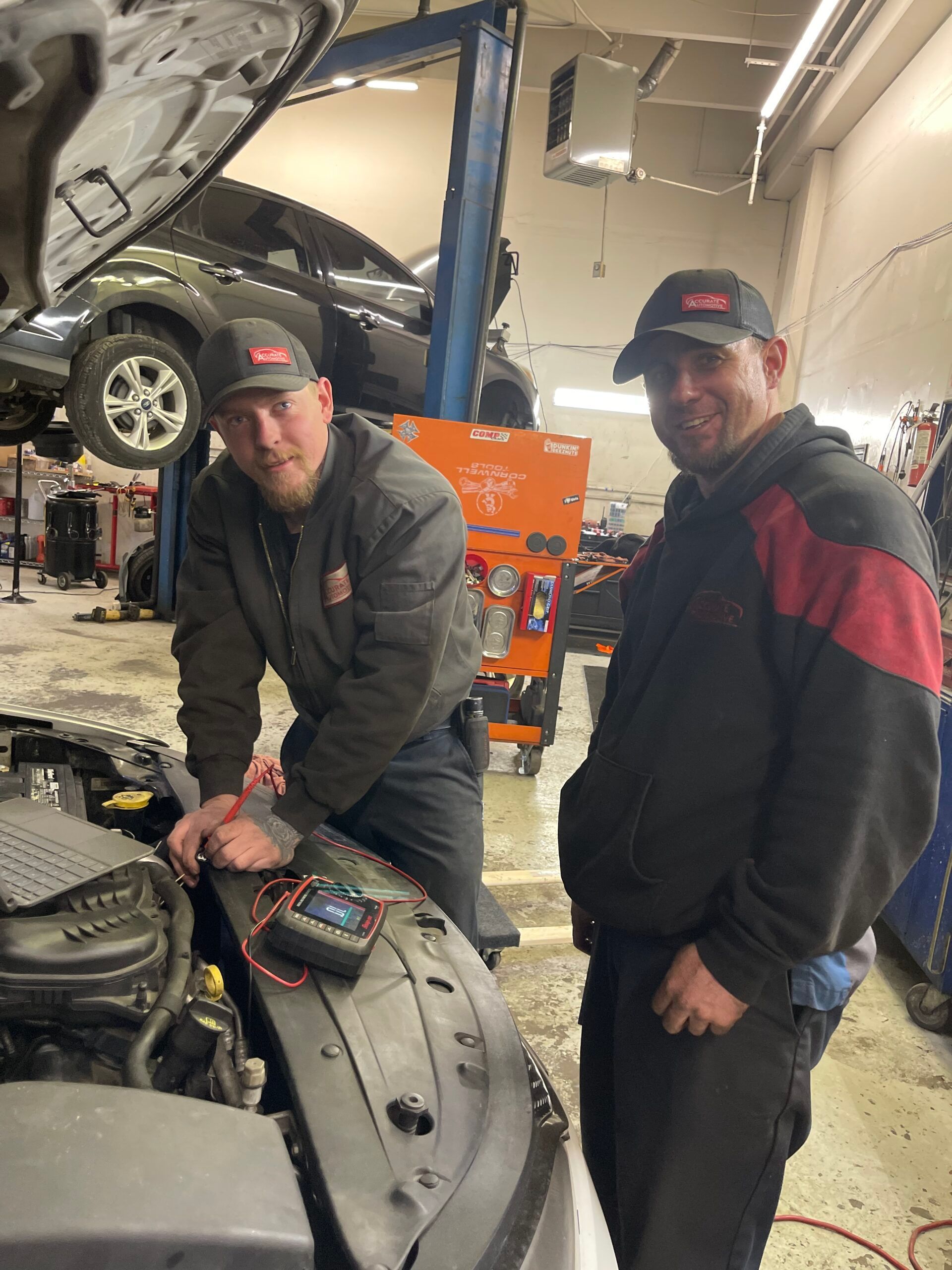 Two mechanics standing by an open car hood in an auto repair shop | Accurate Automotive Northglenn