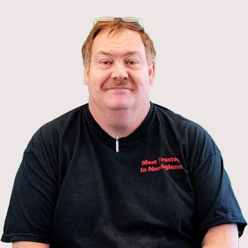 Man in a black T-shirt with red text, smiling against a plain light background | Accurate Automotive Northglenn