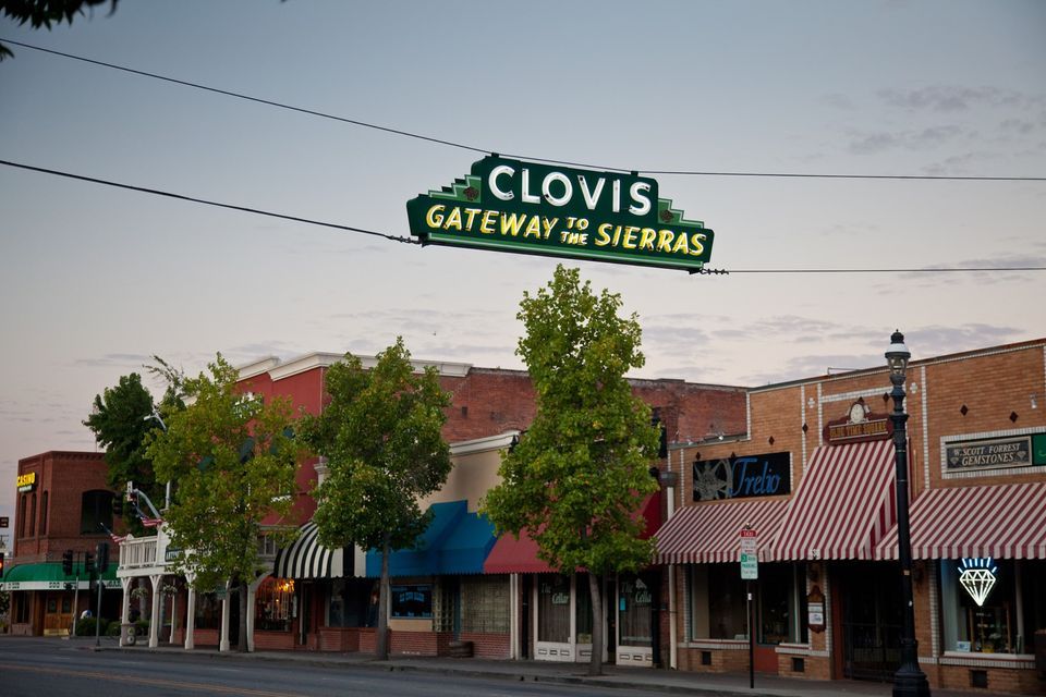 A sign for clovis gateway to sierras hangs over a small town