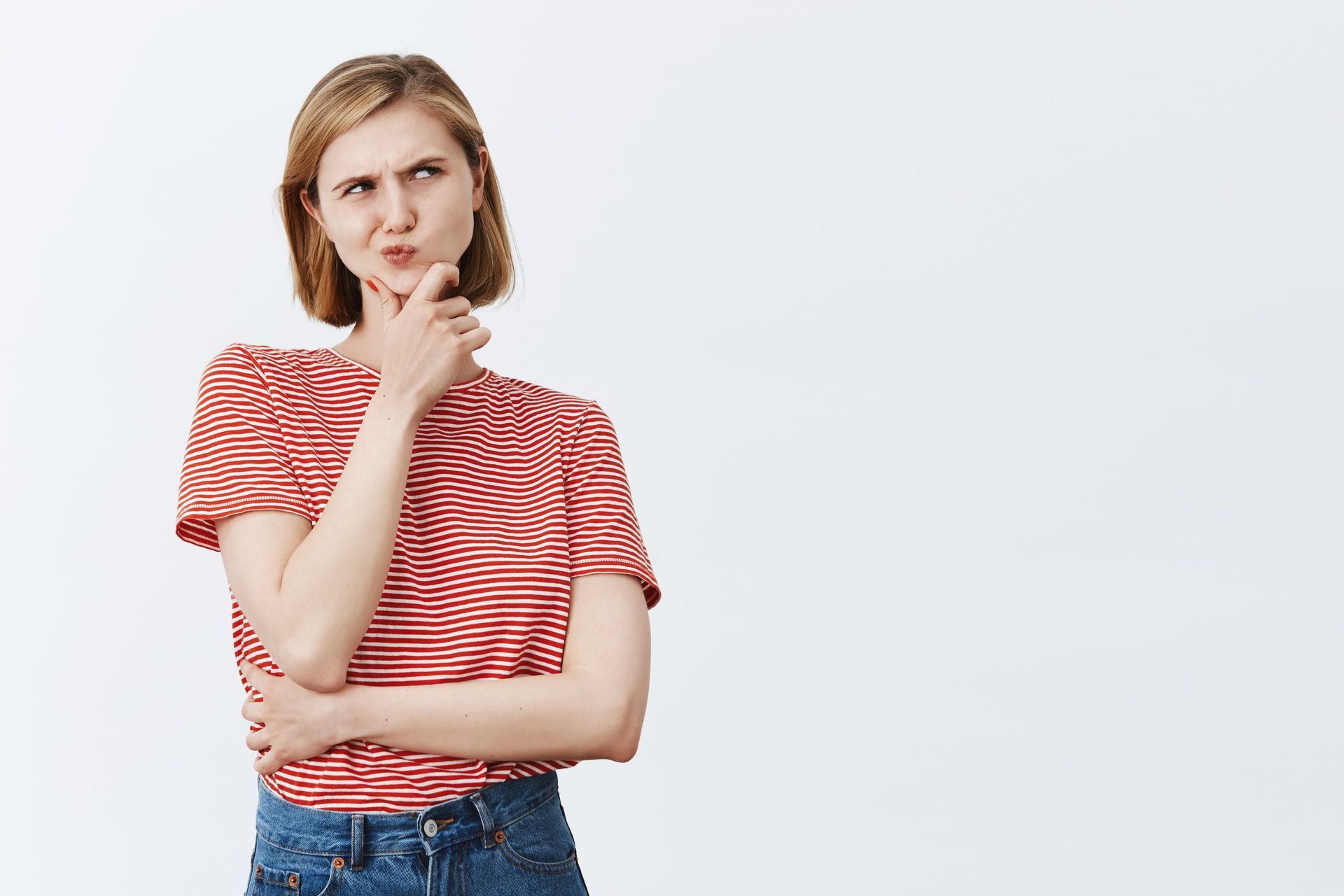 a woman in a red and white striped shirt is holding her hand to her chin .