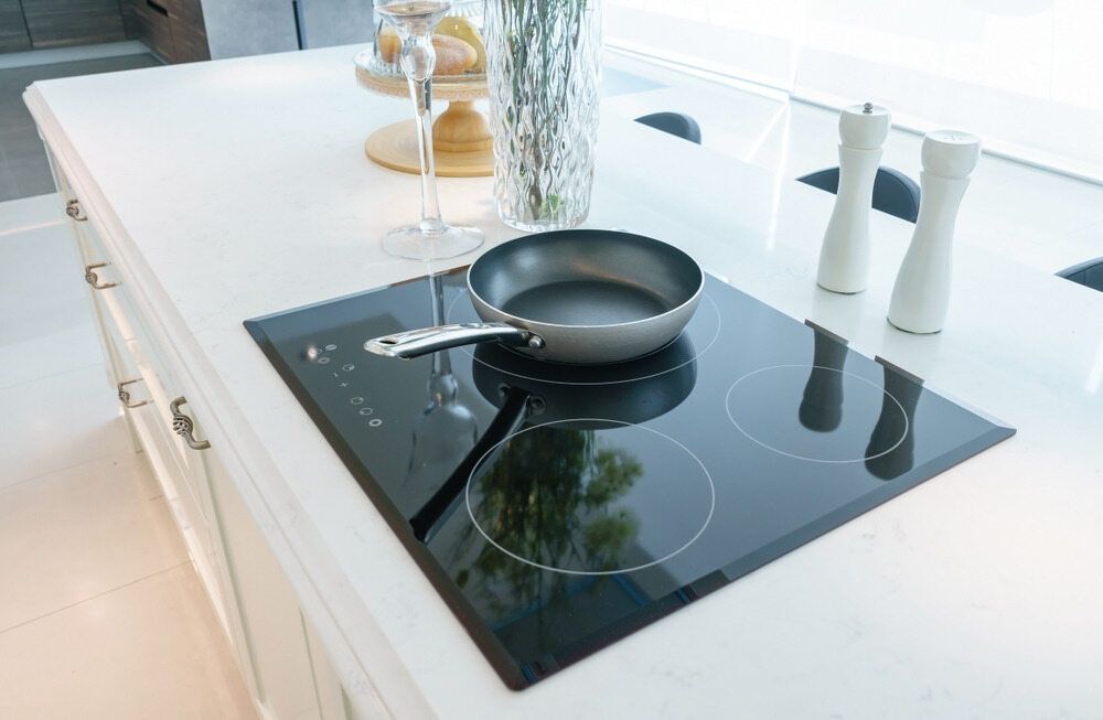 A Kitchen with White Cabinets, stove top oven, sink and a hood — The Latest Home Appliances in Rockhampton