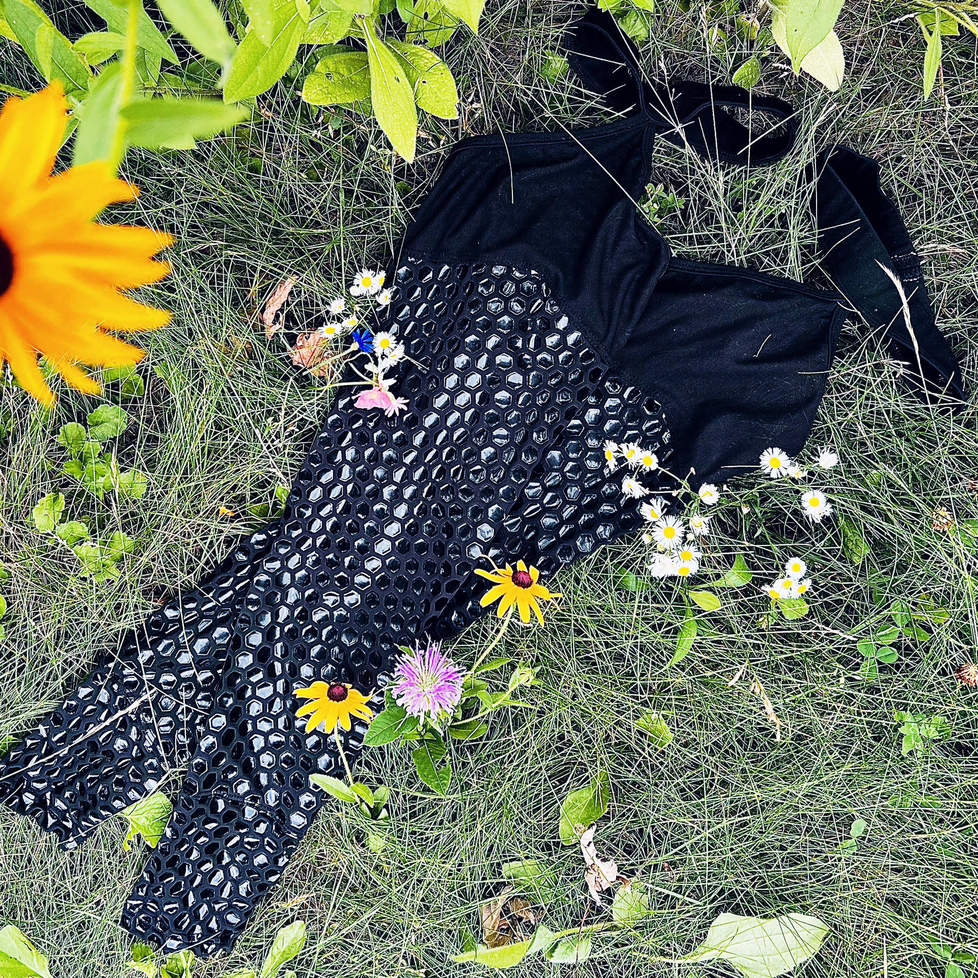 Woman in black lingerie standing outdoors between wooden posts, holding babies breath flowers. Sticky Grippy Pole-wear