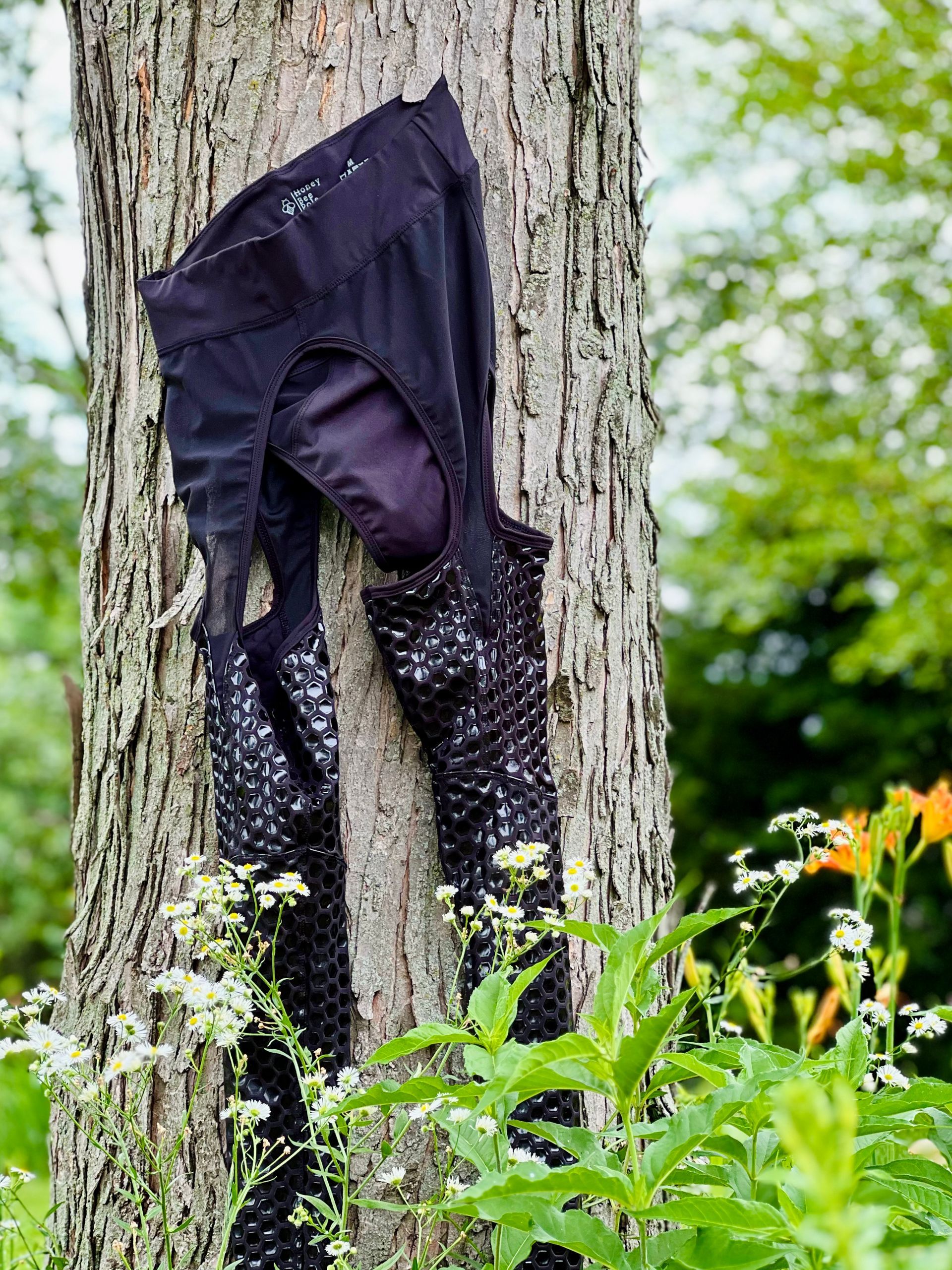Person in red top and black leggings posing in tall grass with overlaid text “The Tease.” Sticky Grippy Pole-wear