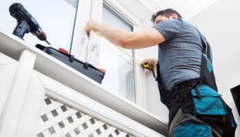 Picture of a handymen completing a window repair on a white house.