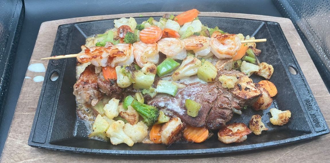 Grilled shrimp and vegetables served on a cast iron skillet.
