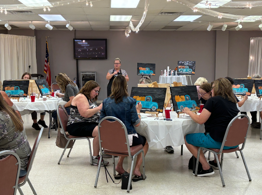 A large room with tables and chairs set up for a wedding reception.