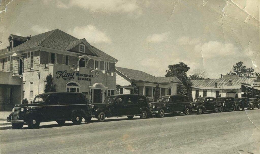 Vintage parade of classic cars lined along a street beside a decorated building