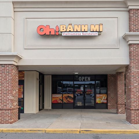 Storefront of Oh Bánh Mì restaurant with brick columns and glass doors, open sign visible