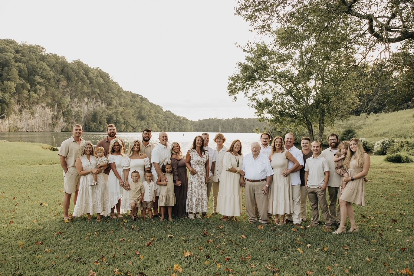 A large family is posing for a picture in front of a lake.