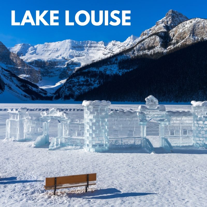 Snowy Lake Louise with mountains, blue sky, ice sculptures, and a bench in the foreground.