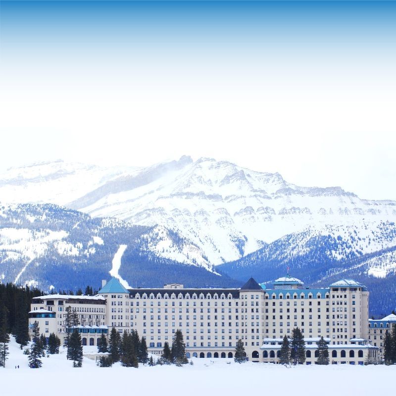 Snowy mountain landscape behind a large hotel or resort building under a clear blue sky
