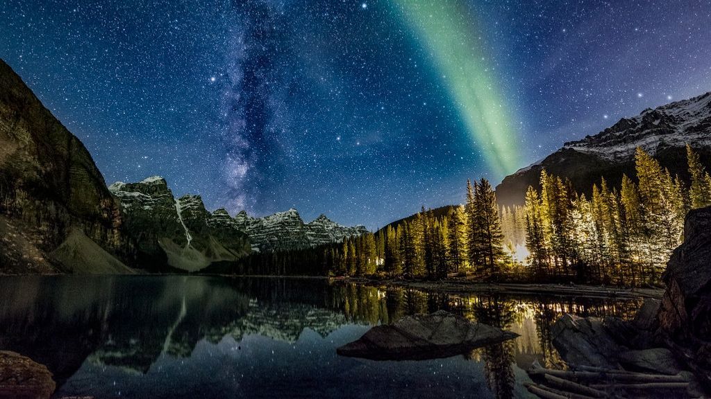 Sunset mountain reflected in a lake, with a bear and cub inset in the lower right.