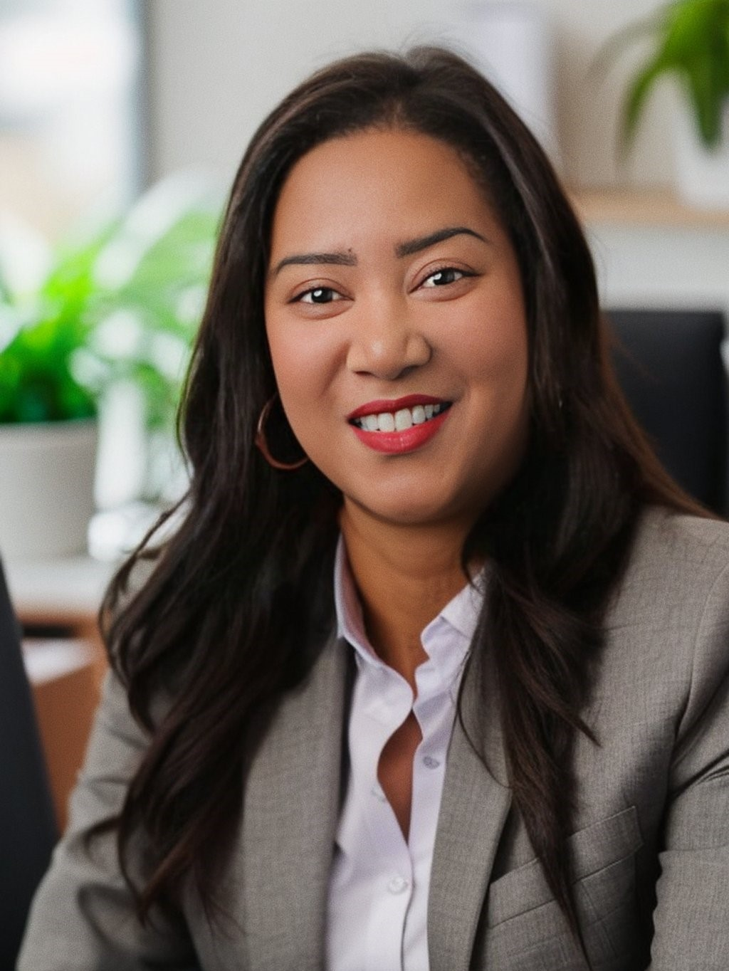 A woman in a suit and white shirt is smiling for the camera.