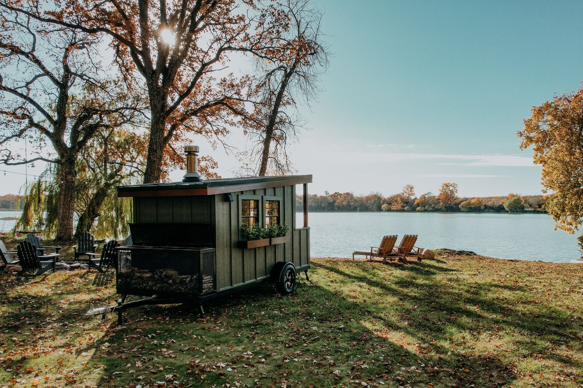 A trailer is parked in a field next to a lake.