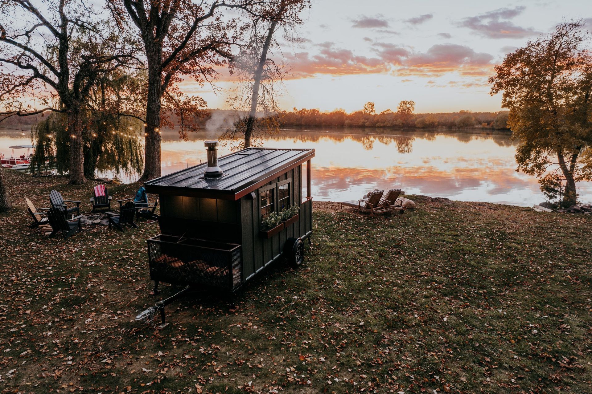 A trailer is parked in a field next to a lake at sunset.