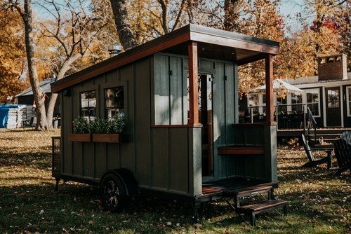 A small house on wheels is parked in a grassy field.