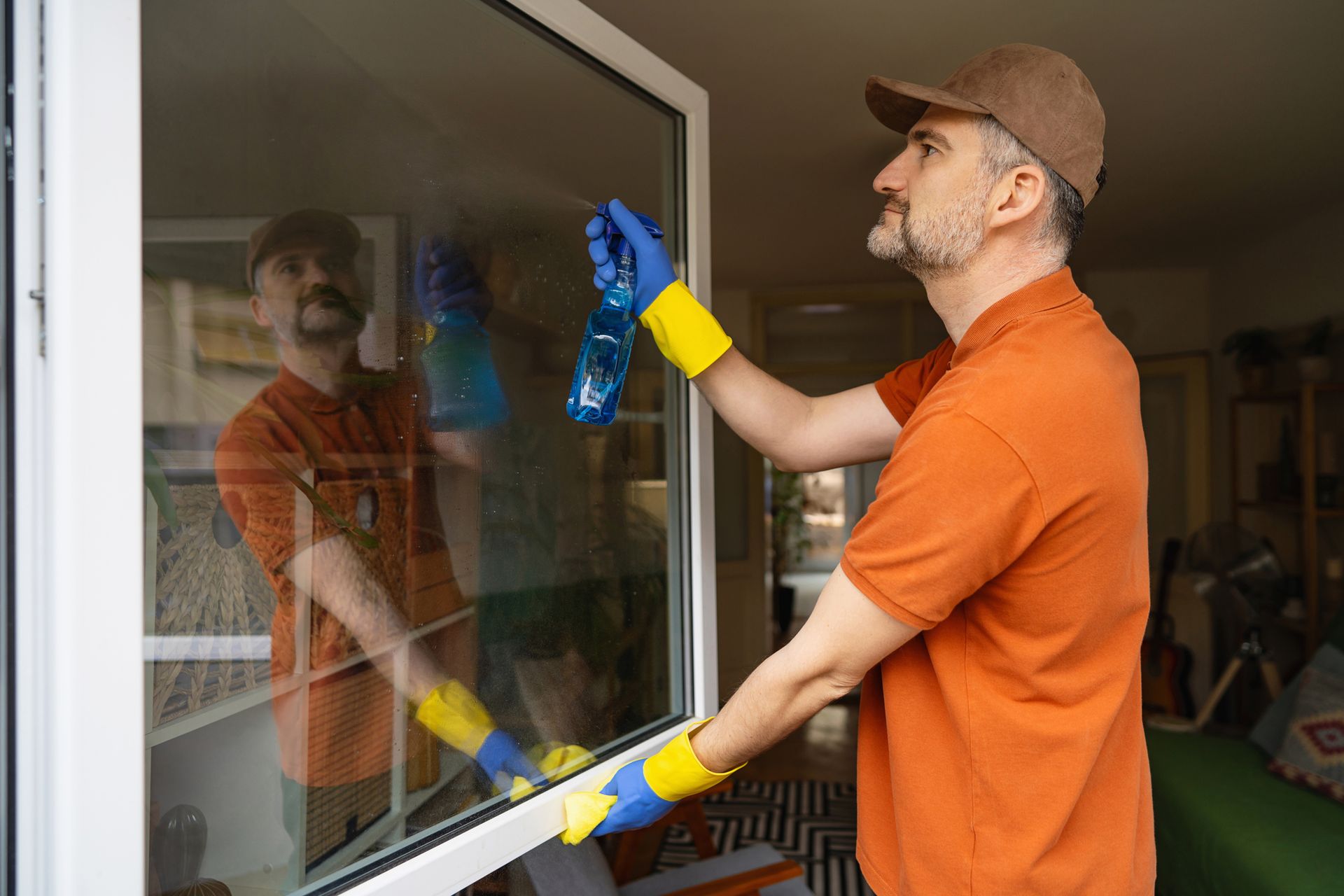 A man is cleaning a window with a spray bottle.