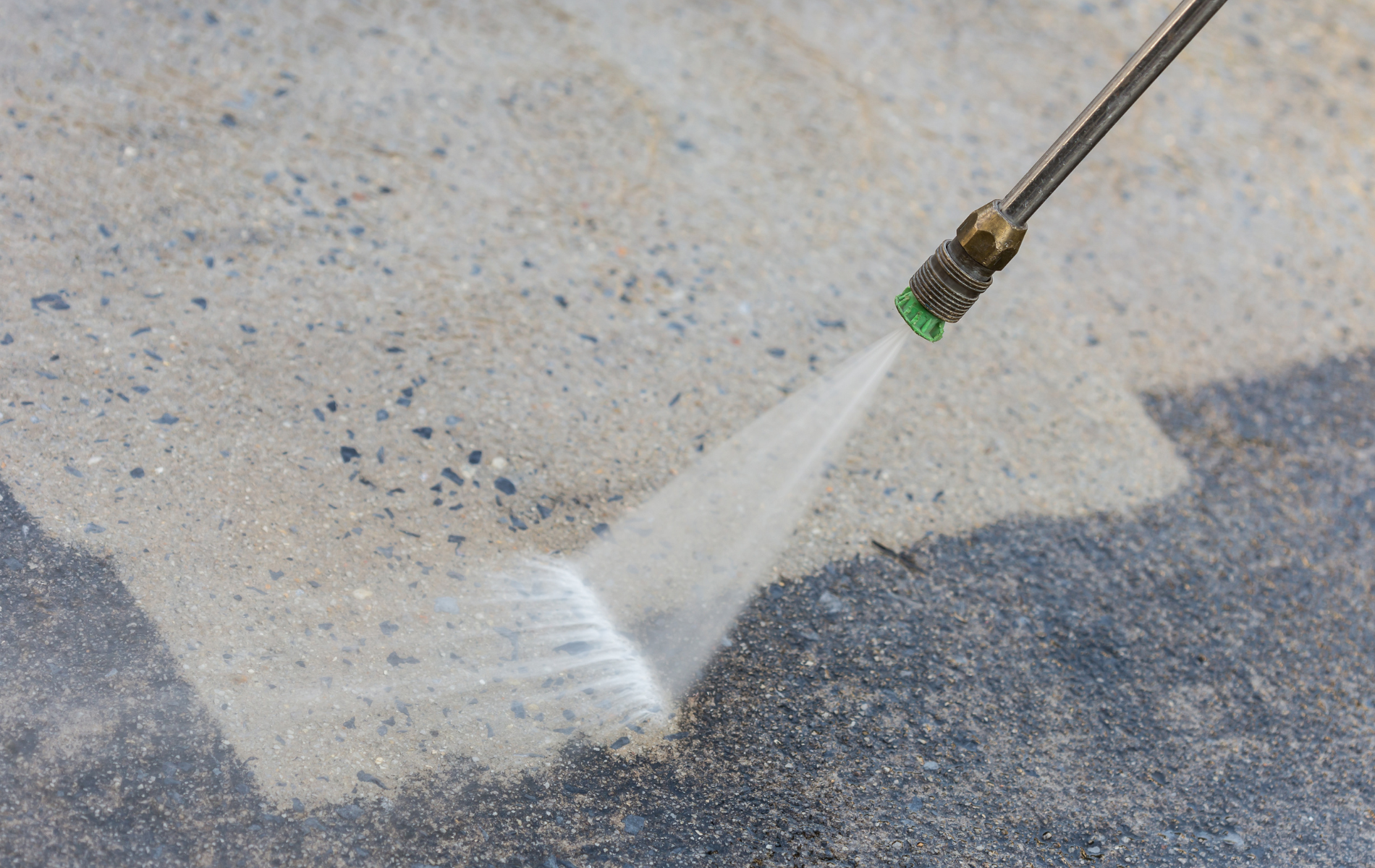 A man wearing black gloves is cleaning a tile floor with a spatula.
