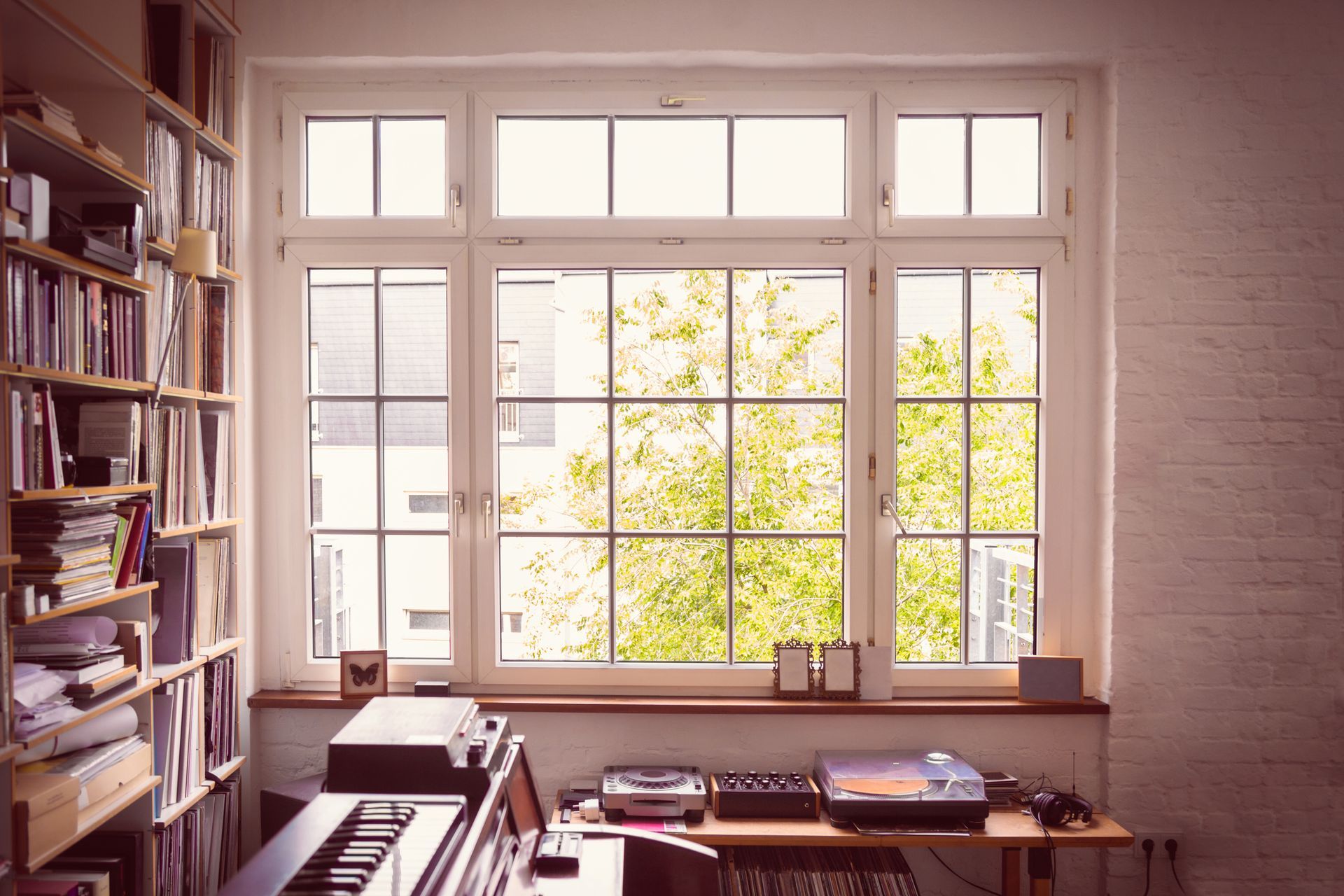 A room with a large window and a piano in front of it.