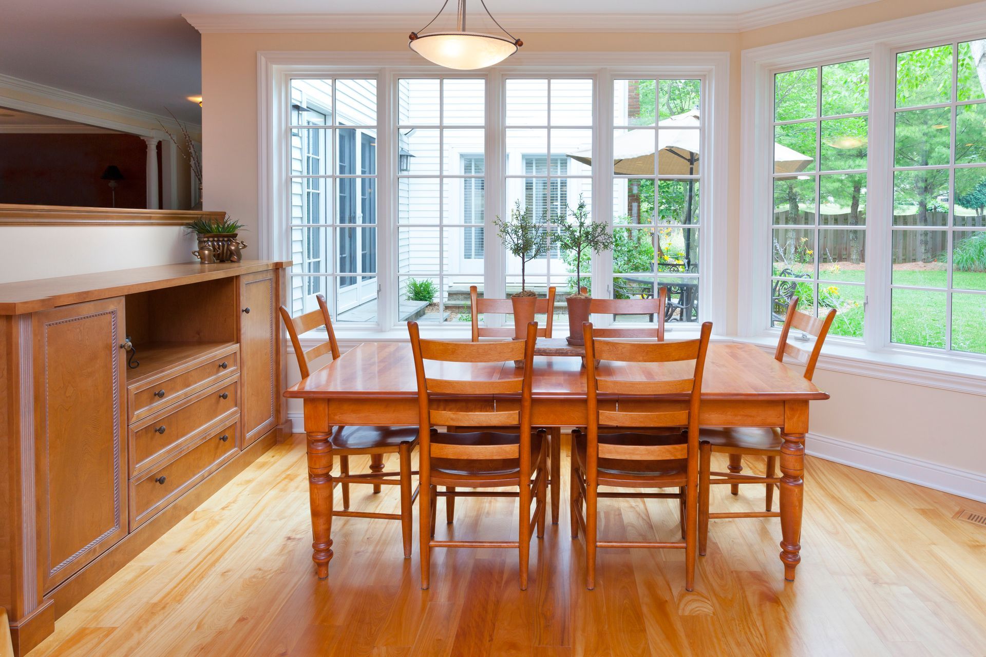 A dining room with a table and chairs and lots of windows