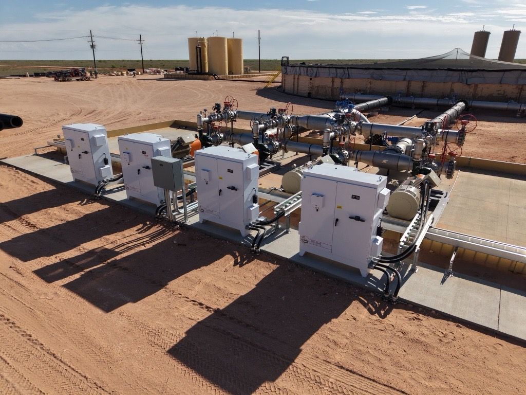 Industrial equipment on a desert site, with white machinery rows and tanks under a clear sky.