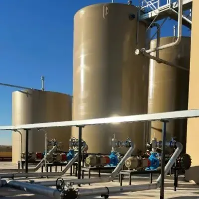 Industrial tanks and piping at a refinery, with blue sky overhead